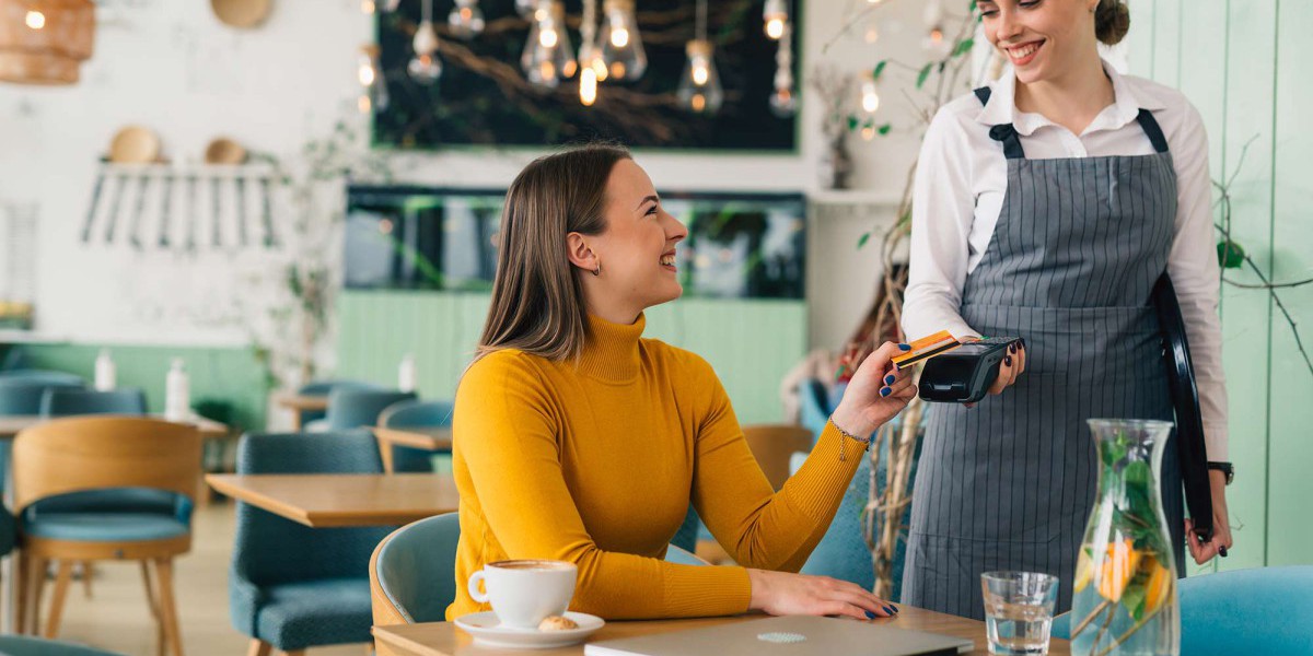 Woman sat at table taking payment using a card machine